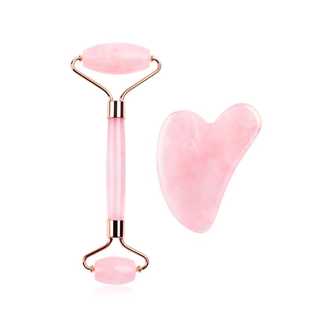 Pink facial roller and gua sha tool on a white background